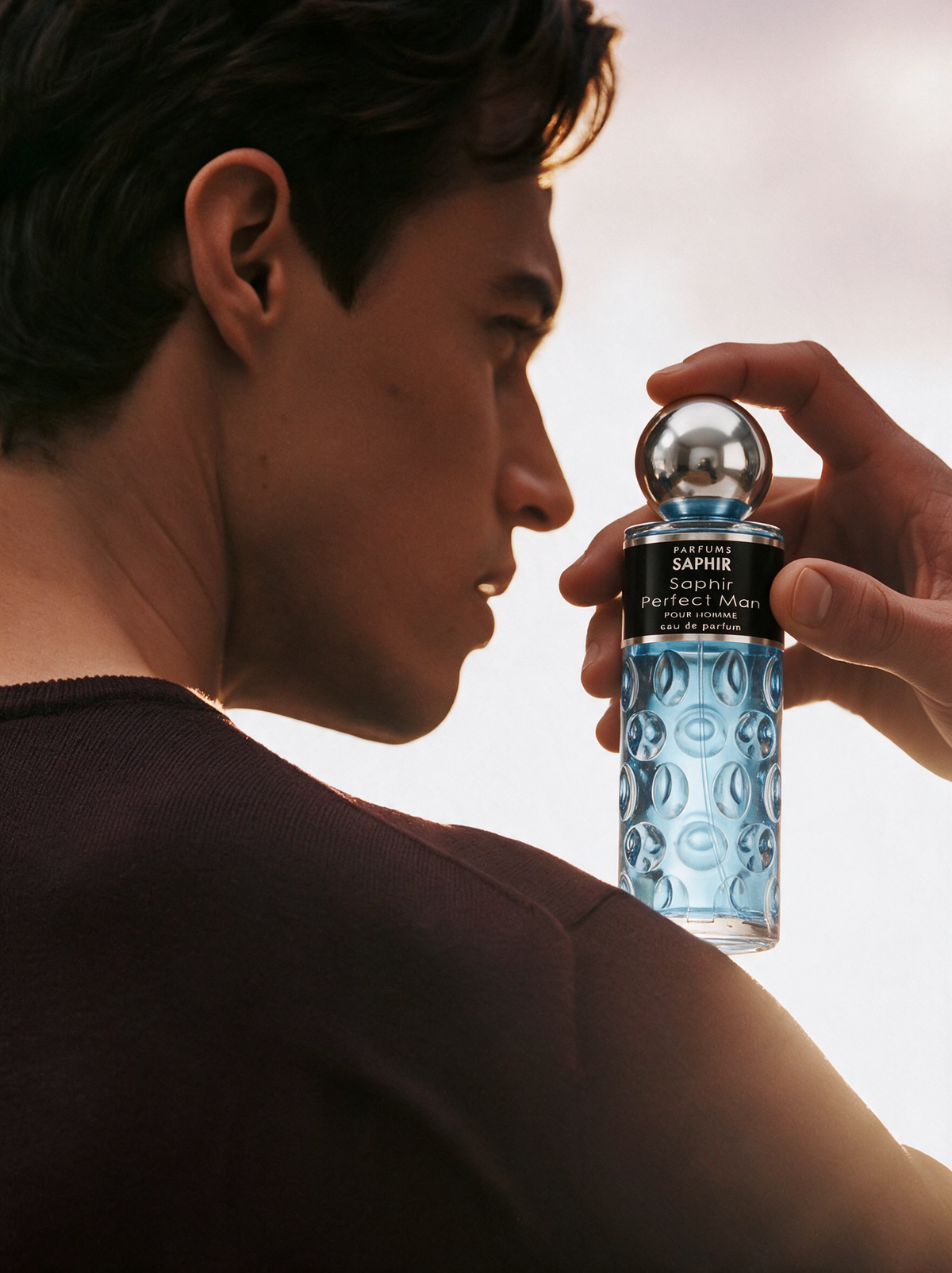 Man applying Saphir Perfect Man eau de parfum, blue fragrance bottle with silver cap