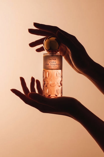 Silhouette hands holding Vida de Saphir perfume bottle, warm backlit tone