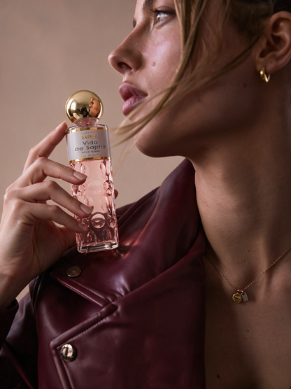 Woman holding Vida de Saphir perfume bottle, pink floral eau de parfum for women